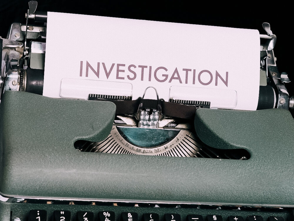 una macchina da scrivere con un foglio bianco e la scritta investigation